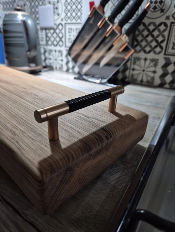 A wooden cutting board with a handle, showcasing a smooth surface and natural grain patterns.
