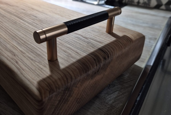 A wooden cutting board with a handle, showcasing a smooth surface and natural grain patterns.